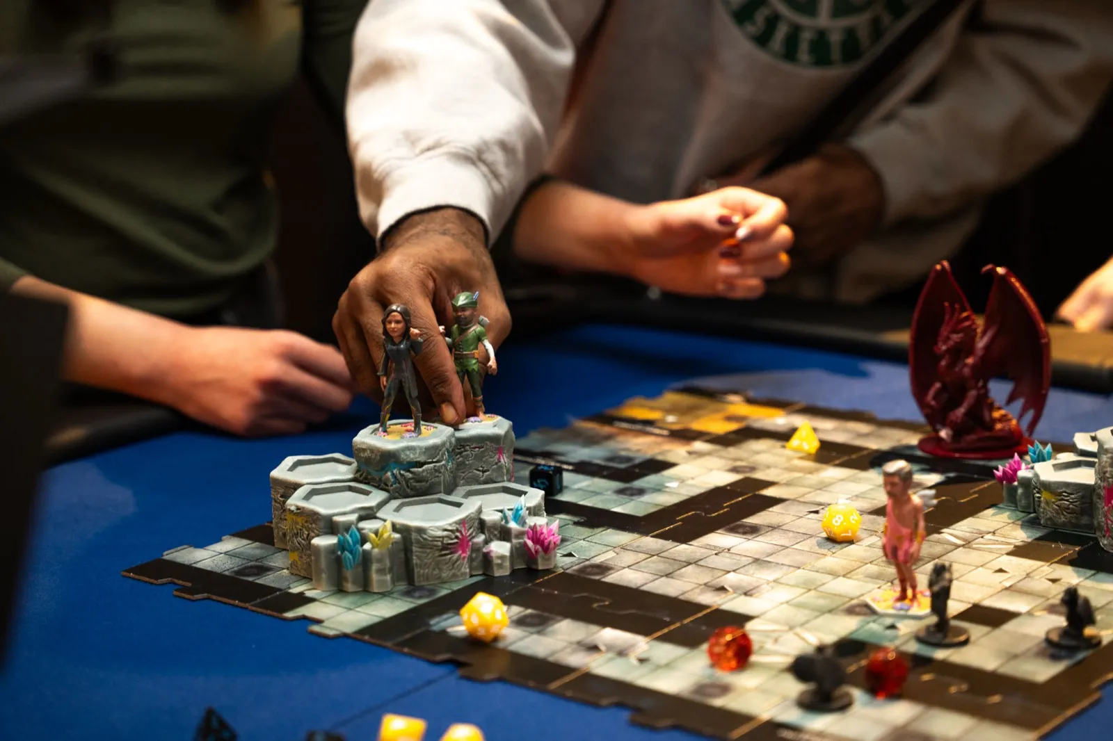 Players moving Minikin figurines across a dungeon map during a tabletop game